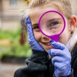 Girl looking through magnifying glass